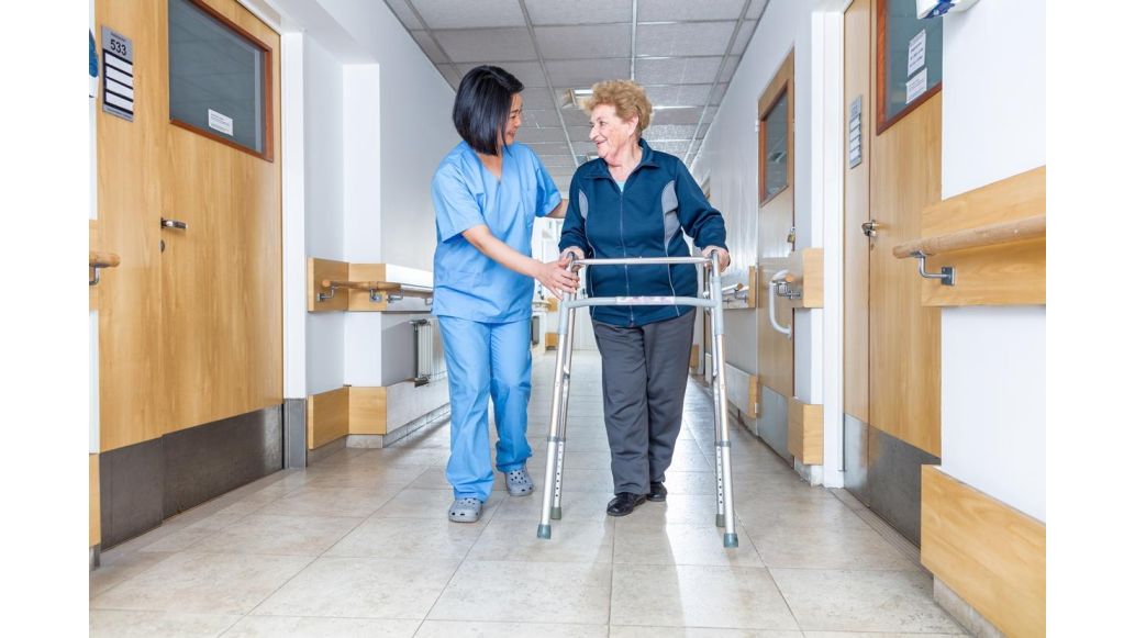 nurse helping senior woman with walker
